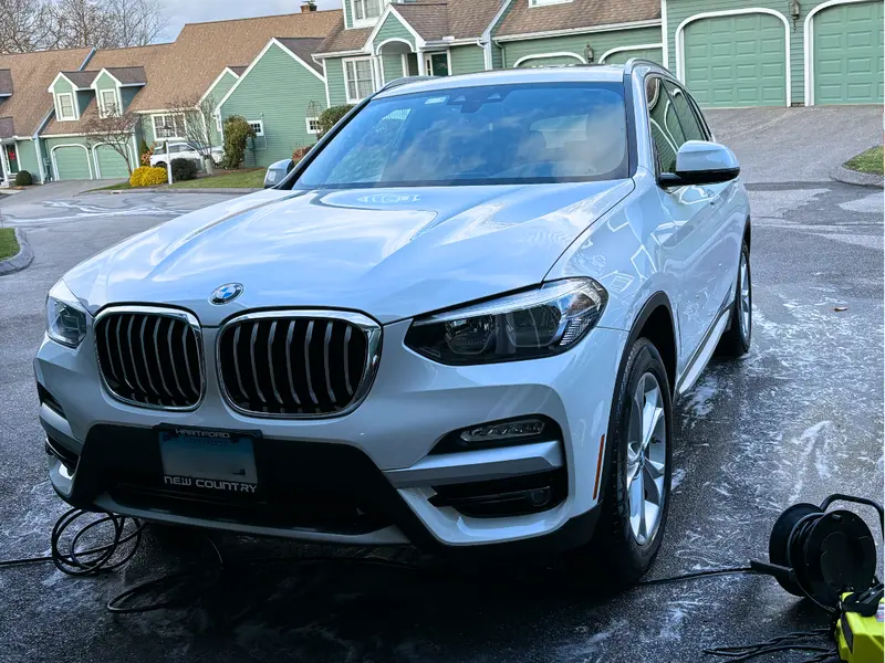 Polished white BMW exterior with mirror-like finish and restored paint after professional car detailing